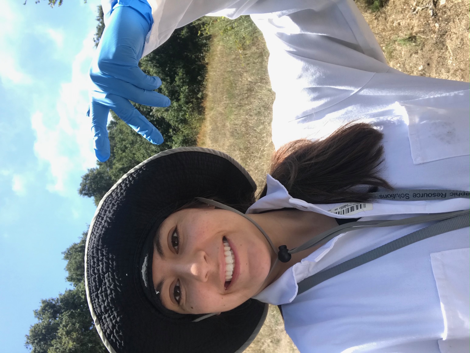 Student poses while conducting research in grassy field